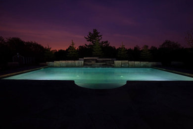 Diseño de piscina con fuente alargada clásica de tamaño medio rectangular en patio trasero con losas de hormigón