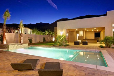 На фото: большой прямоугольный бассейн на заднем дворе в современном стиле с мощением тротуарной плиткой и домиком у бассейна