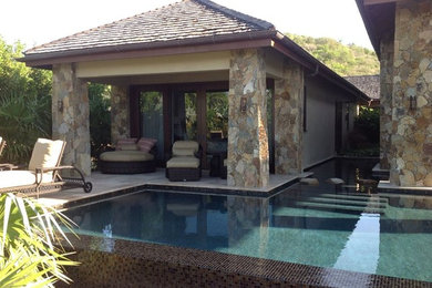 Example of a large backyard stone and custom-shaped pool house design in Miami