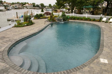 Ejemplo de piscina con fuente natural tradicional de tamaño medio tipo riñón en patio trasero con adoquines de piedra natural