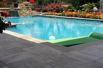 Ejemplo de piscina con fuente en patio trasero con suelo de baldosas