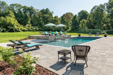 Foto de piscina con fuente alargada actual grande rectangular en patio trasero con adoquines de piedra natural