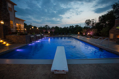 Diseño de piscina con fuente alargada tradicional renovada grande rectangular en patio trasero con losas de hormigón