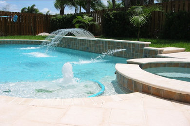 Modelo de piscinas y jacuzzis naturales de tamaño medio a medida en patio trasero con adoquines de hormigón