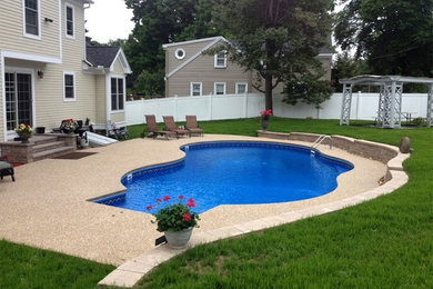 Imagen de casa de la piscina y piscina alargada grande a medida en patio trasero con adoquines de hormigón