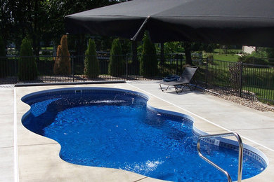 Pool - backyard concrete and custom-shaped pool idea in New York