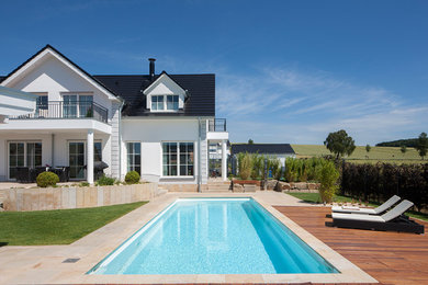 Großer Mediterraner Pool hinter dem Haus in rechteckiger Form mit Natursteinplatten in Sonstige