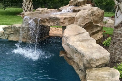 シャーロットにある広いトロピカルスタイルのおしゃれな裏庭プール (噴水、天然石敷き) の写真