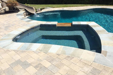 Imagen de piscina tradicional renovada grande a medida en patio trasero con adoquines de piedra natural