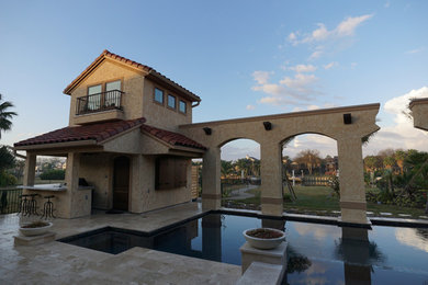 Example of a huge tuscan backyard custom-shaped pool house design in Houston