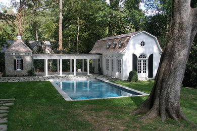 Ejemplo de casa de la piscina y piscina natural tradicional grande rectangular en patio trasero con adoquines de hormigón