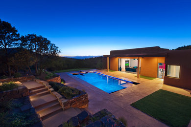 Diseño de casa de la piscina y piscina alargada actual de tamaño medio rectangular en patio trasero con losas de hormigón