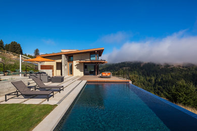 This is an example of a contemporary rectangular infinity swimming pool in San Francisco with concrete paving.
