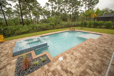 Mid-sized minimalist backyard brick and custom-shaped infinity pool photo in Miami