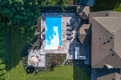 Ejemplo de piscina clásica renovada grande rectangular en patio trasero con paisajismo de piscina y adoquines de piedra natural