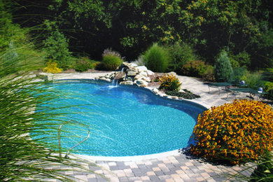 Large backyard stamped concrete and custom-shaped lap pool photo in New York