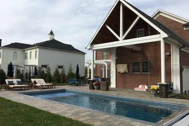 Modelo de piscina marinera de tamaño medio rectangular en patio trasero con adoquines de hormigón