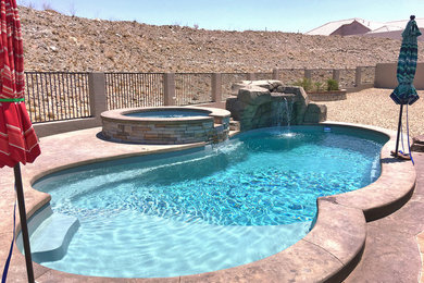 Imagen de piscina actual grande redondeada en patio trasero con adoquines de piedra natural