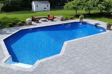 Modelo de piscina con fuente alargada contemporánea grande a medida en patio trasero con adoquines de piedra natural