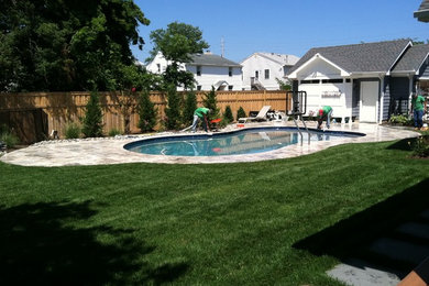 Imagen de piscina natural clásica de tamaño medio a medida en patio trasero con adoquines de piedra natural