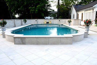 Imagen de piscina elevada clásica grande a medida en patio trasero con suelo de hormigón estampado