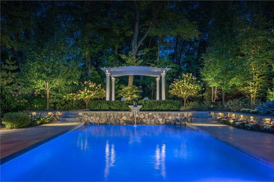Photo of a medium sized traditional back rectangular natural swimming pool in Boston with a water feature and stamped concrete.