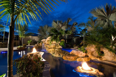 Ejemplo de piscinas y jacuzzis alargados exóticos extra grandes a medida en patio trasero con adoquines de piedra natural