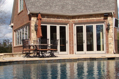 Imagen de casa de la piscina y piscina natural tradicional grande a medida en patio trasero con adoquines de hormigón