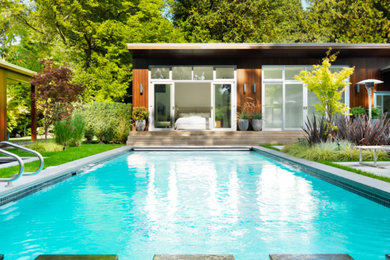 Ejemplo de piscina rectangular en patio trasero con adoquines de hormigón