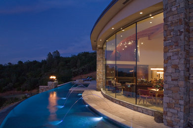 Diseño de piscina con fuente infinita contemporánea extra grande a medida en patio trasero con adoquines de hormigón