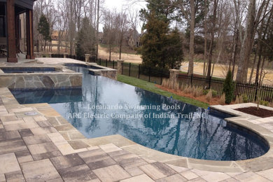 Hot tub - backyard tile and custom-shaped infinity hot tub idea in Charlotte