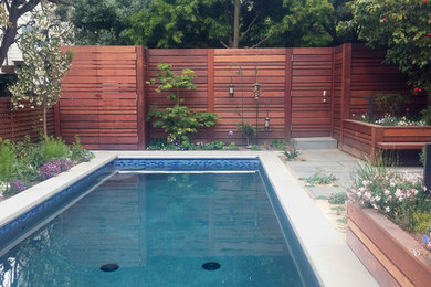 Diseño de piscina alargada contemporánea pequeña rectangular en patio trasero con adoquines de piedra natural
