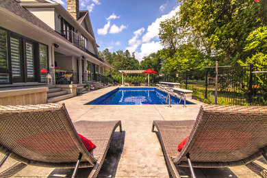 Imagen de piscina alargada clásica renovada de tamaño medio rectangular en patio trasero con losas de hormigón