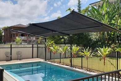 Modelo de piscina natural moderna de tamaño medio rectangular en patio trasero con entablado