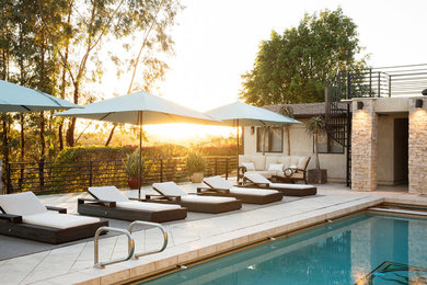Imagen de piscina alargada contemporánea grande rectangular en patio trasero con adoquines de piedra natural