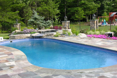 Diseño de piscina con fuente alargada contemporánea grande a medida en patio trasero con adoquines de piedra natural