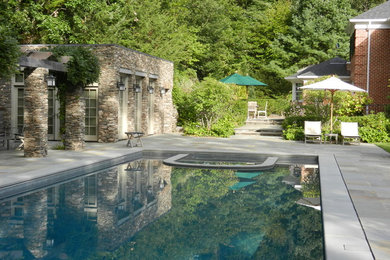 Foto di una grande piscina monocorsia tradizionale rettangolare dietro casa con una vasca idromassaggio e pavimentazioni in pietra naturale