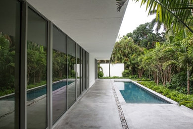 Foto de casa de la piscina y piscina alargada minimalista rectangular en patio lateral con losas de hormigón