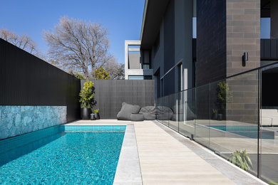 Imagen de piscinas y jacuzzis contemporáneos rectangulares en patio trasero con adoquines de piedra natural