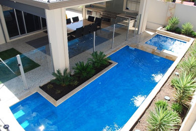 Diseño de piscinas y jacuzzis alargados minimalistas de tamaño medio rectangulares en patio trasero con adoquines de piedra natural