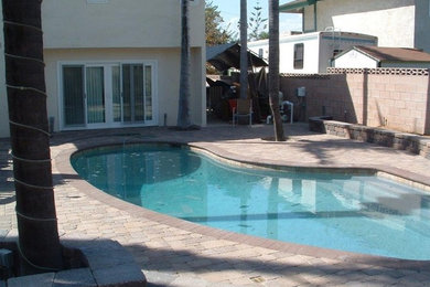 Imagen de piscina tradicional de tamaño medio tipo riñón en patio trasero con adoquines de hormigón