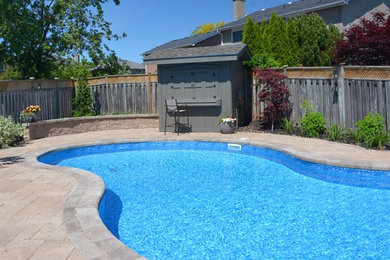 Imagen de casa de la piscina y piscina alargada tradicional de tamaño medio tipo riñón en patio trasero con adoquines de hormigón