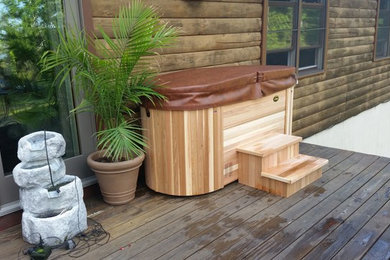 Hot tub - traditional backyard round aboveground hot tub idea in Other with decking