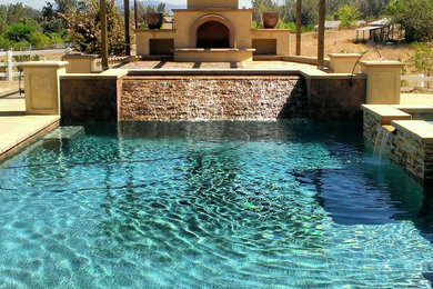 Ejemplo de piscina con fuente alargada mediterránea grande rectangular en patio trasero con adoquines de piedra natural