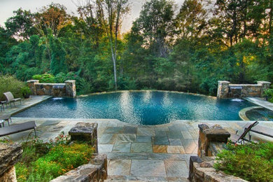 Modelo de piscinas y jacuzzis clásicos renovados a medida en patio trasero con adoquines de piedra natural