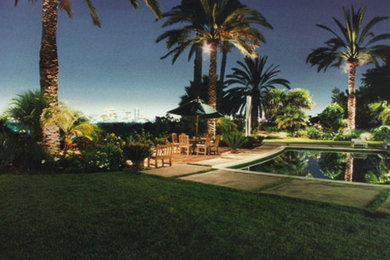 Imagen de piscina natural clásica grande a medida en patio trasero con losas de hormigón