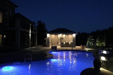 Imagen de casa de la piscina y piscina actual de tamaño medio tipo riñón en patio trasero con suelo de hormigón estampado