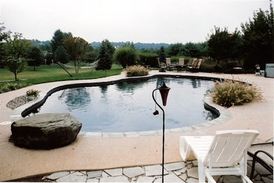 Imagen de piscina alargada de tamaño medio a medida en patio trasero con adoquines de hormigón