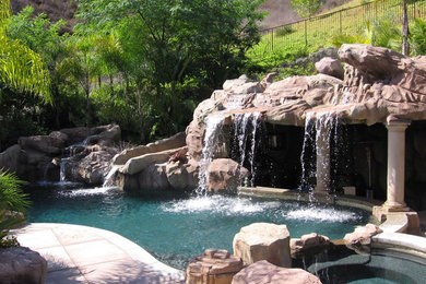 Ejemplo de piscina con fuente elevada tropical a medida