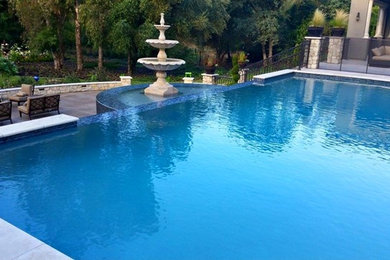 Large mediterranean back rectangular infinity swimming pool in Sacramento with a water feature and concrete slabs.